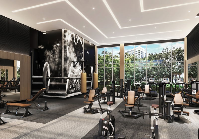 Sixth & Rio luxury and ultra luxury preconstruction condos in Fort Lauderdale, Florida, fitness center with strength machines, free weights and cardio equipment under dramatic lighting and tall windows.
