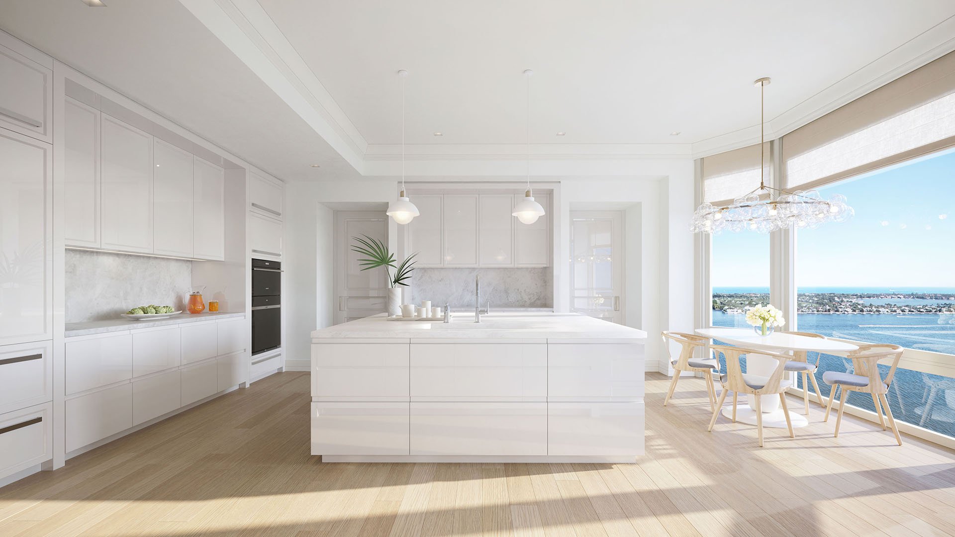 Chef kitchen with an oversized island, breakfast area and broad water views at South Flagler House in West Palm Beach, highlighting luxury and ultra luxury condos with bright contemporary finishes.