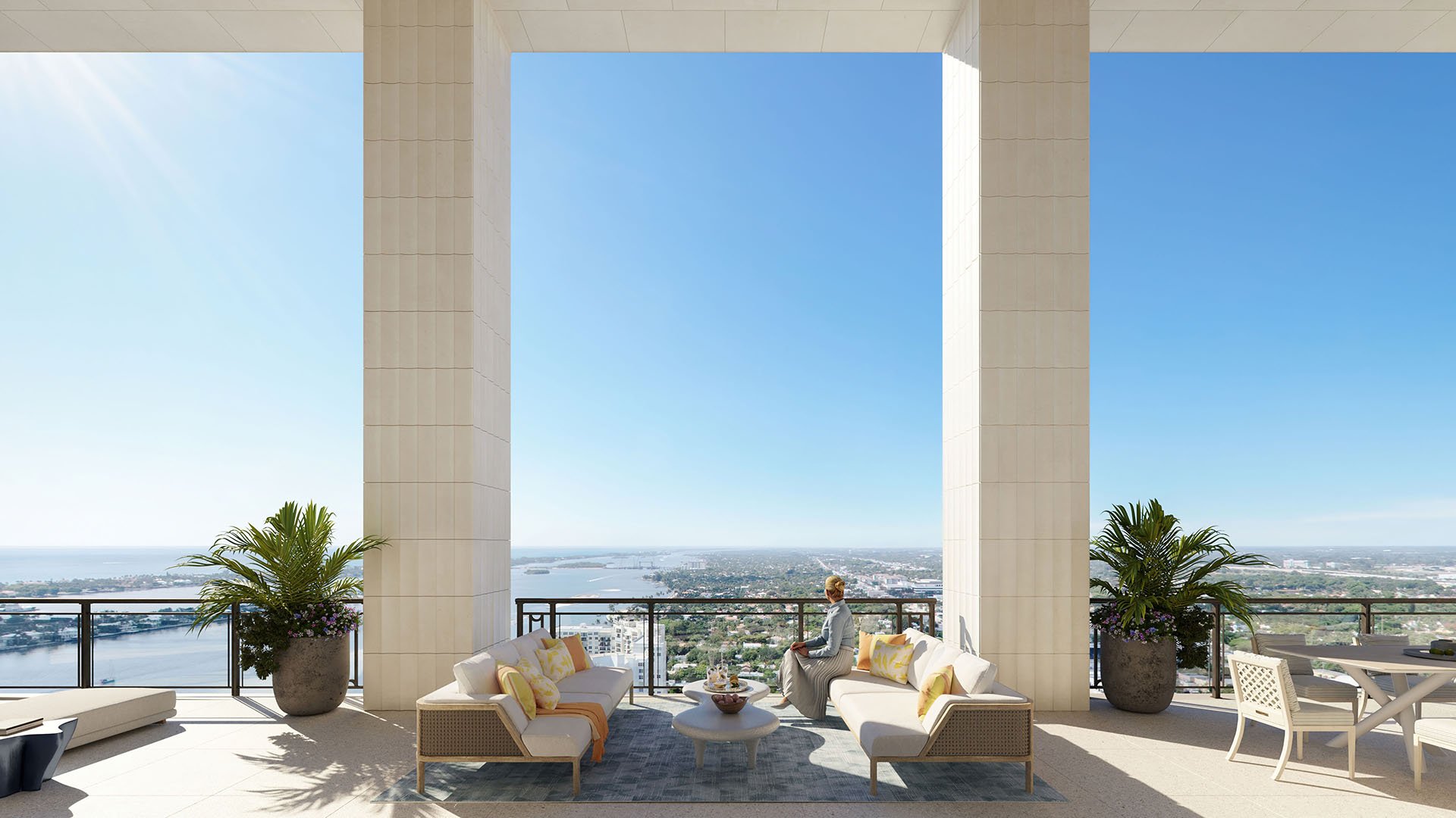 Columned outdoor loggia lounge with sofas, dining area and a sweeping waterfront panorama at South Flagler House in West Palm Beach, presenting luxury and ultra luxury condos with elevated terrace living.