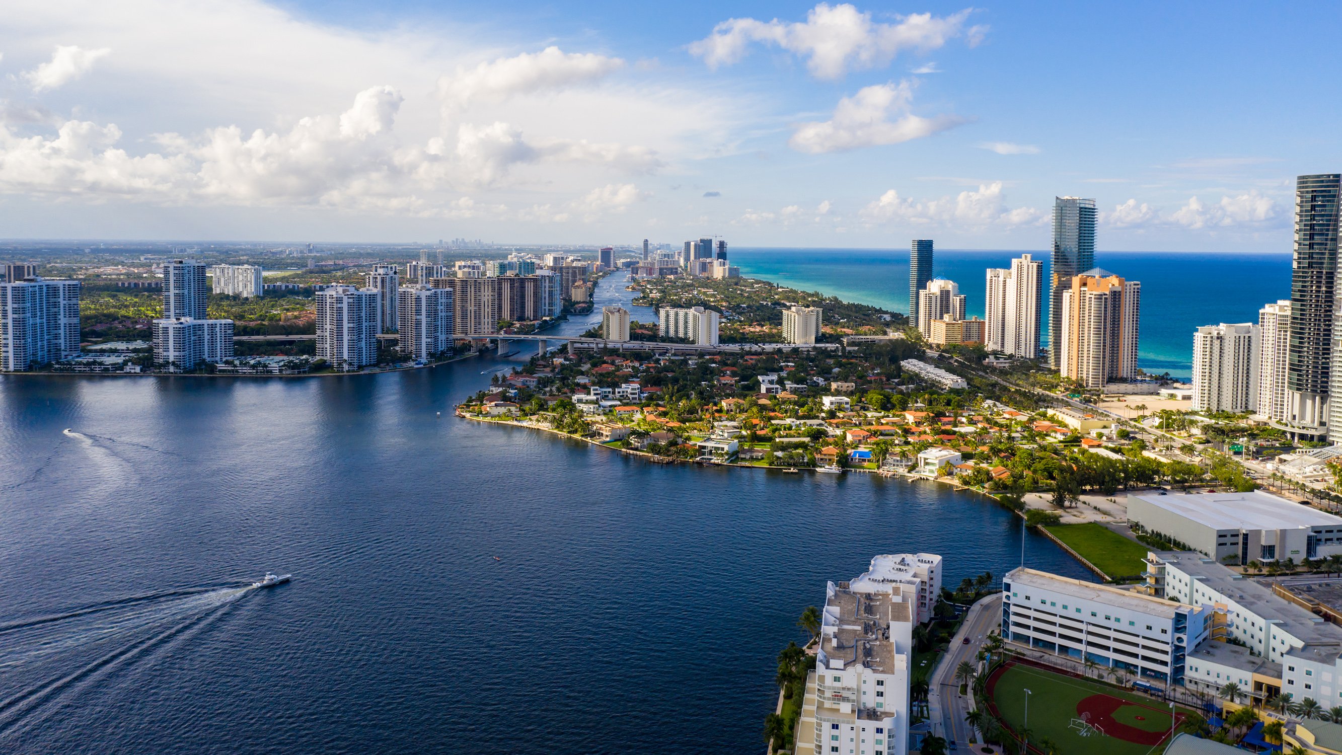 Sunny Isles Beach, Miami coastal aerial over barrier island and high‑rises, hotspot for luxury and ultra luxury condos; preconstruction and resale. Featuring view.