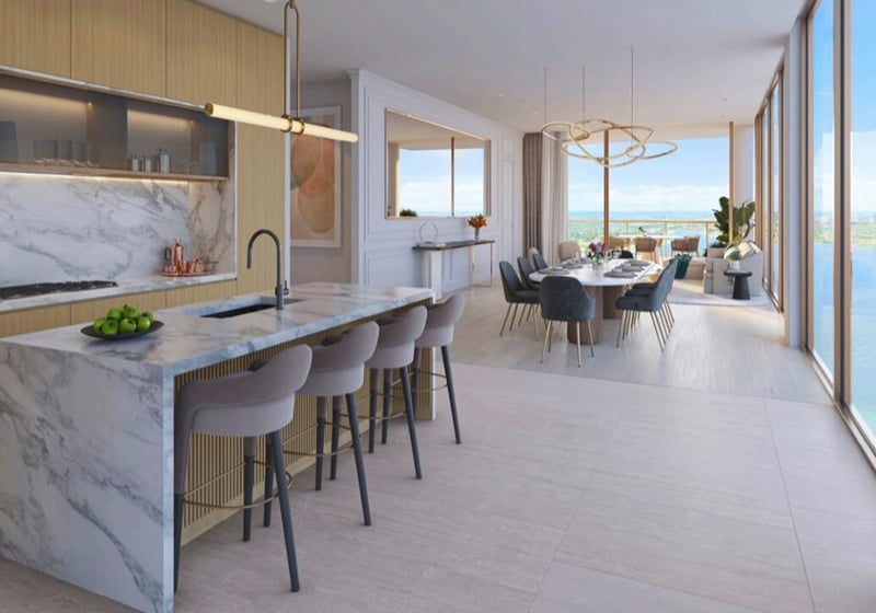 Open chef kitchen with a waterfall marble island, dining area, and water views at The Berkeley in West Palm Beach, showcasing luxury and ultra luxury condos with seamless entertaining space.