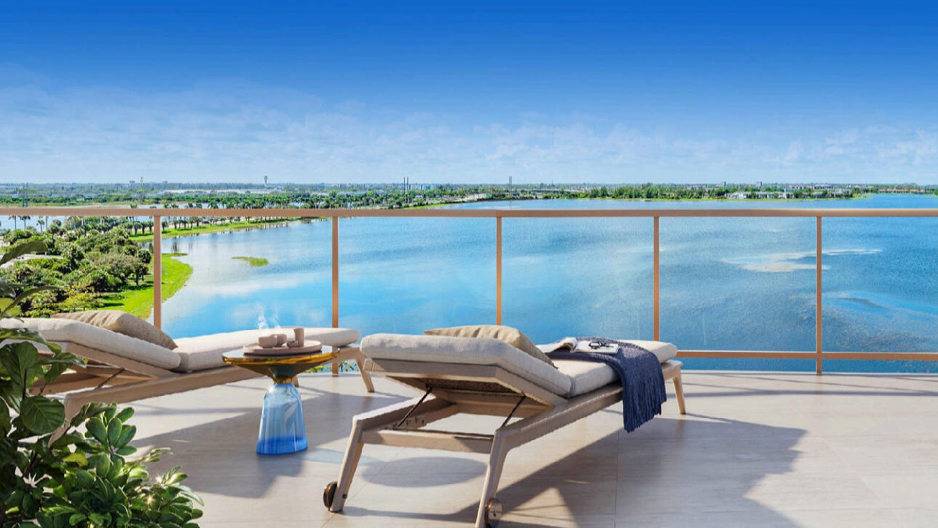 Wide waterfront terrace with chaise lounges and a glass railing at The Berkeley in West Palm Beach, highlighting luxury and ultra luxury condos with serene outdoor relaxation overlooking the water.