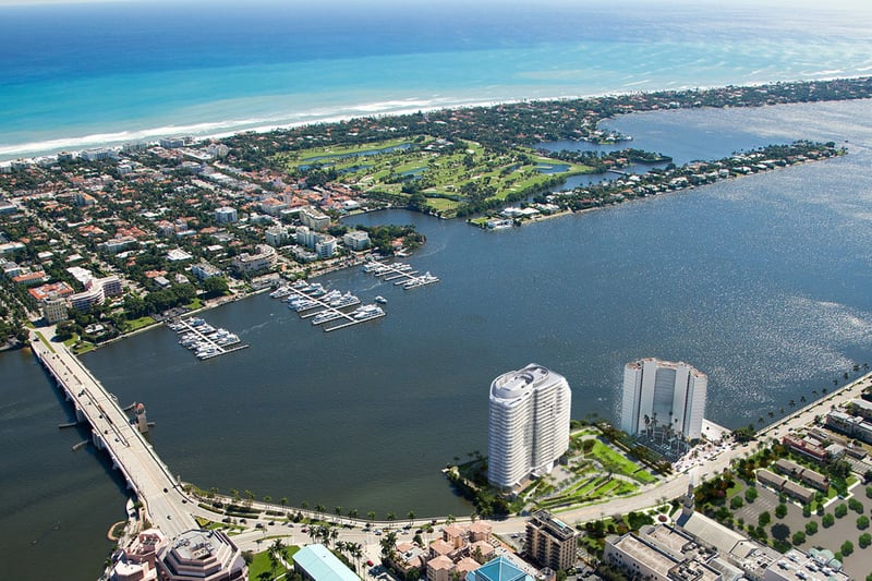 High aerial of coastline, golf course, marina, and a waterfront tower at The Bristol Palm Beach in Palm Beach, highlighting luxury and ultra luxury condos beside ocean and waterway views.