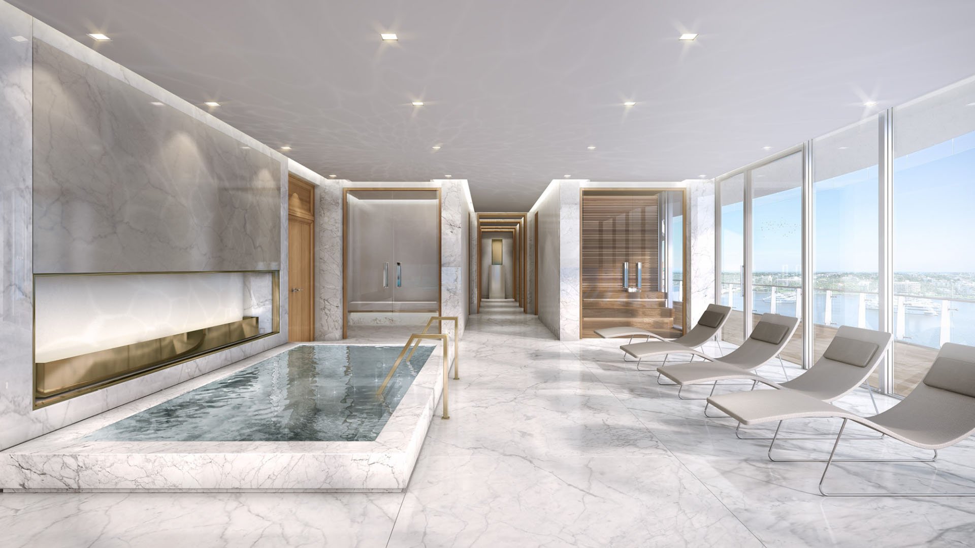 Marble relaxation room with an indoor plunge pool, fireplace, chaise lounges, and water views at The Bristol Palm Beach in Palm Beach, enhancing luxury and ultra luxury condos wellness amenities.