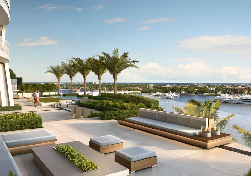 Palm-lined garden terrace with built-in lounge seating overlooking yachts and water at The Bristol Palm Beach in Palm Beach, extending the luxury and ultra luxury condos outdoor amenities.