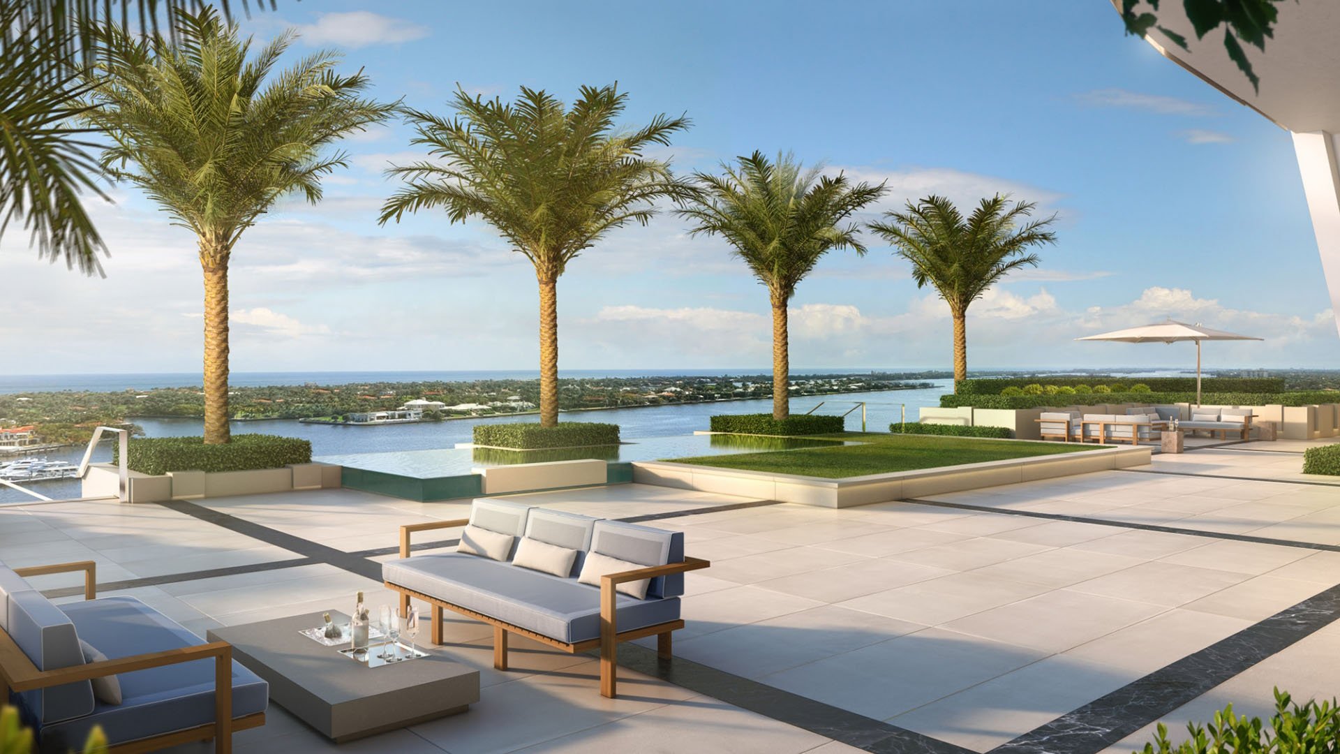Palm-lined terrace lounge with open-air seating and wide waterfront views at The Bristol Palm Beach in Palm Beach, showcasing the luxury and ultra luxury condos outdoor living.