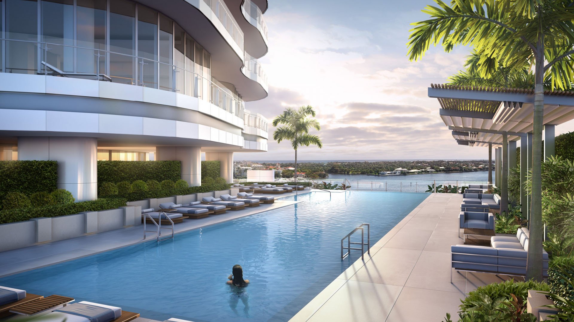 Waterfront lap pool with pergola lounge seating beside the tower at The Bristol Palm Beach in Palm Beach, highlighting resort style amenities for luxury and ultra luxury condos.
