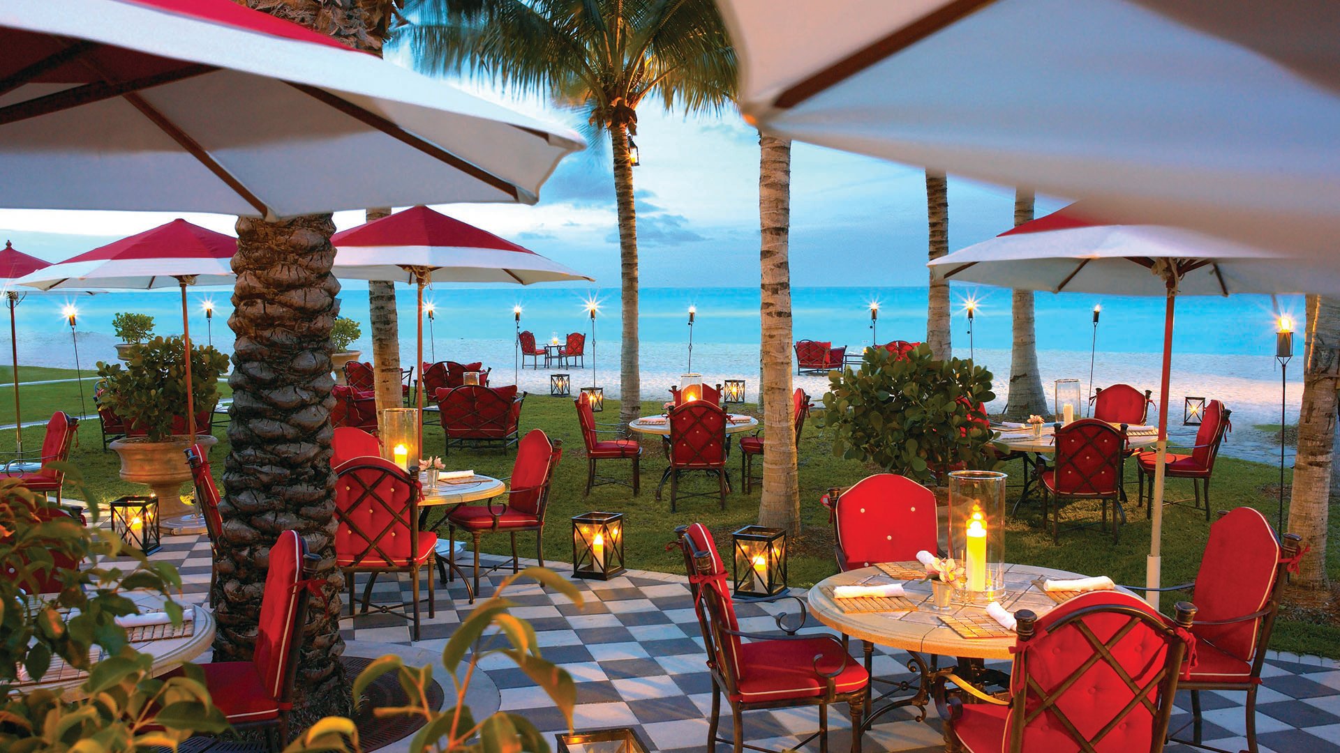 Beach bar and oceanfront terrace dining with umbrellas and tropical seating at The Estates at Acqualina, Sunny Isles Beach, a community of luxury and ultra luxury condos.