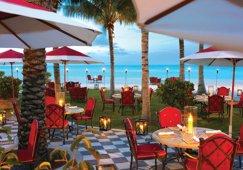 Beach bar and oceanfront terrace dining with umbrellas and tropical seating at The Estates at Acqualina, Sunny Isles Beach, a community of luxury and ultra luxury condos.