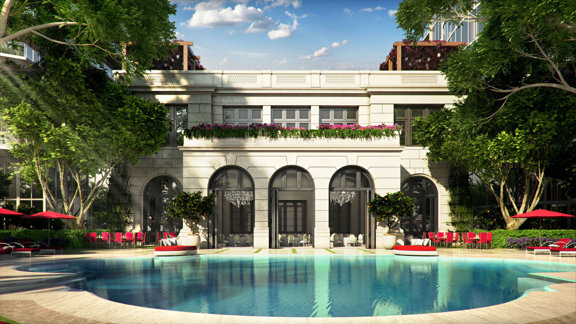 Courtyard pool and clubhouse facade with arches, trees, and reflective water at The Estates at Acqualina, Sunny Isles Beach, a community of luxury and ultra luxury condos.