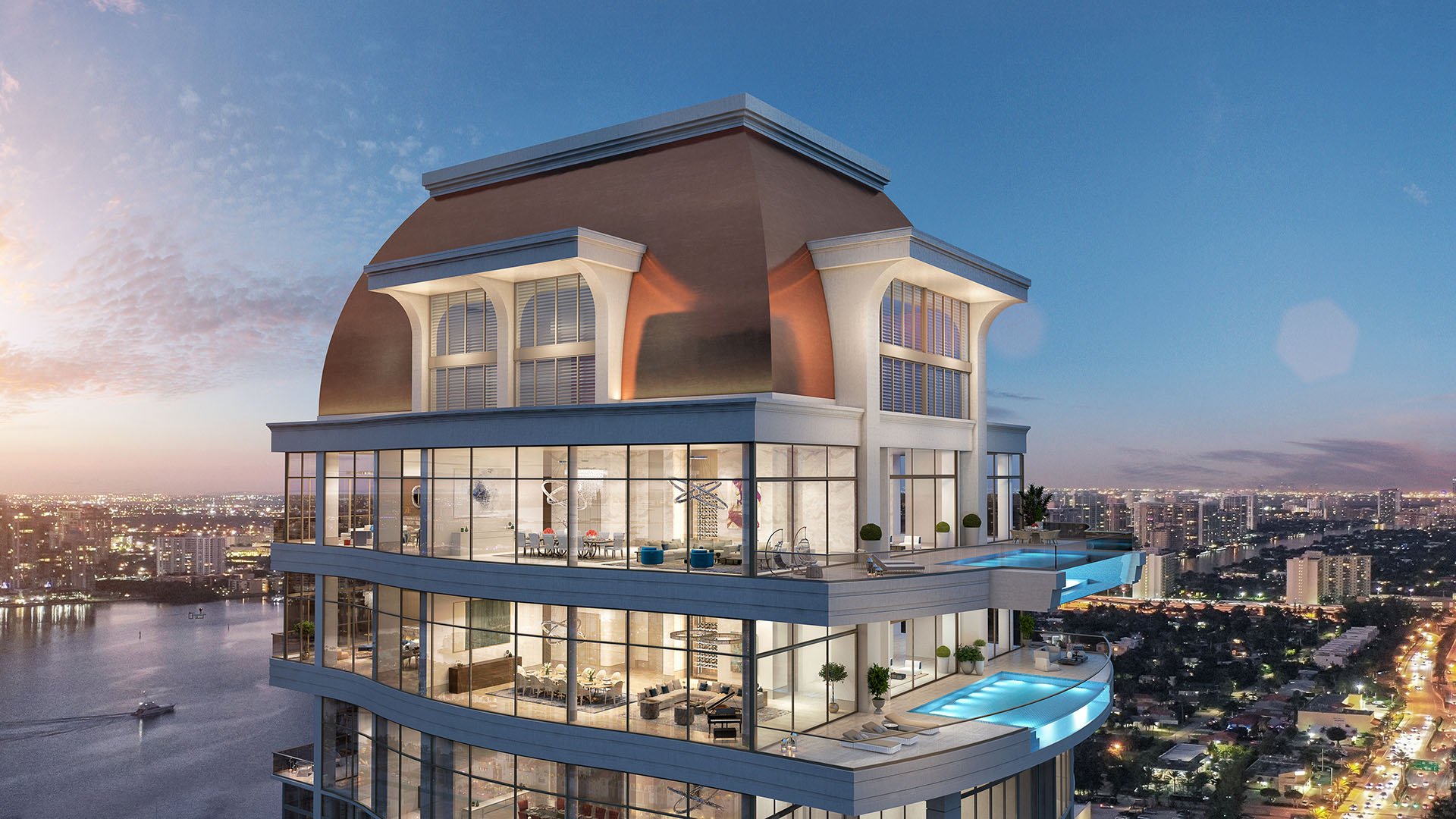 Dusk view of the penthouse crown with illuminated interiors and a sky pool at The Estates at Acqualina, Sunny Isles Beach, a community of luxury and ultra luxury condos.