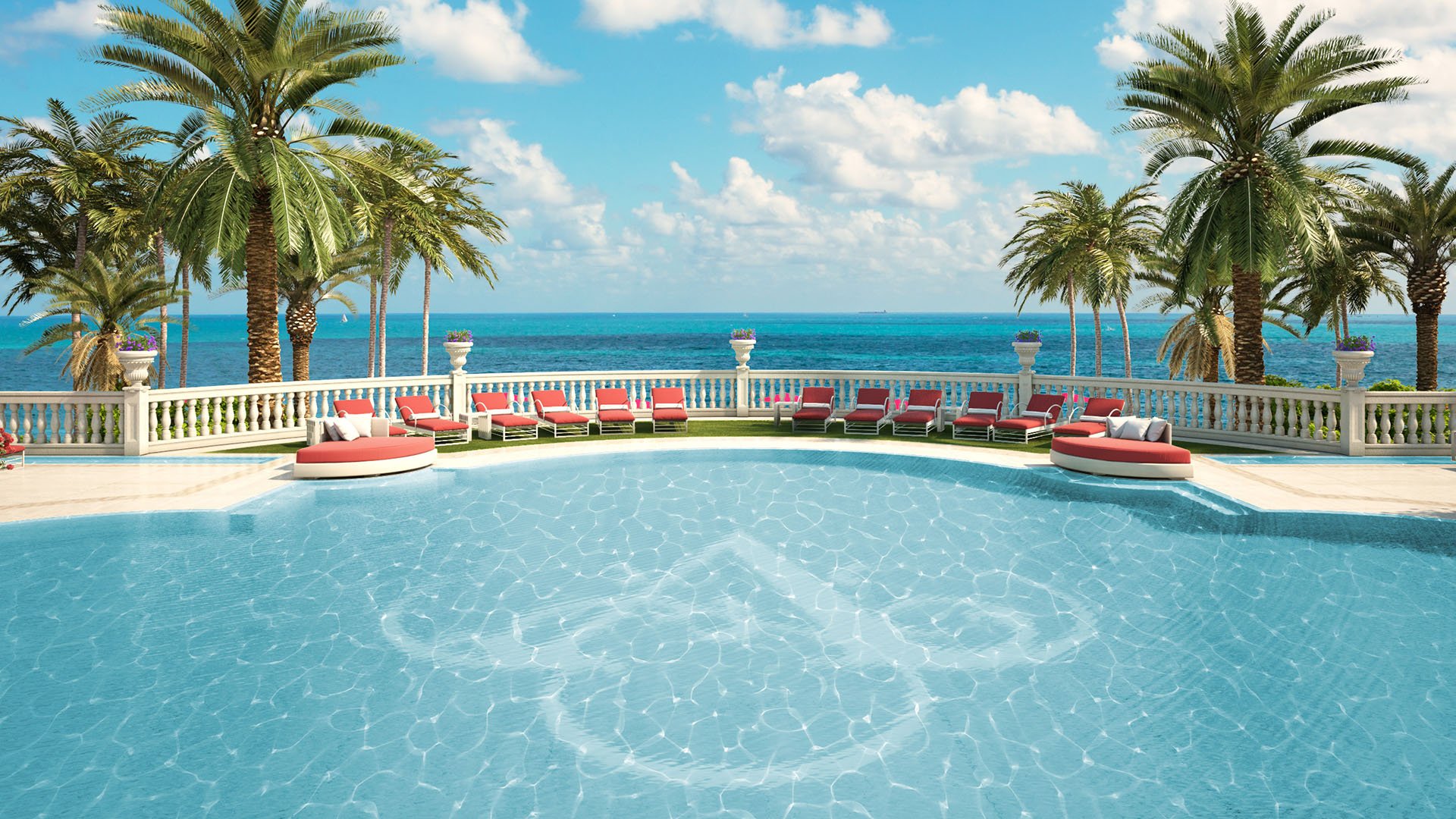 Palm-lined oceanfront pool terrace with loungers and direct water views at The Estates at Acqualina, Sunny Isles Beach, a community of luxury and ultra luxury condos.