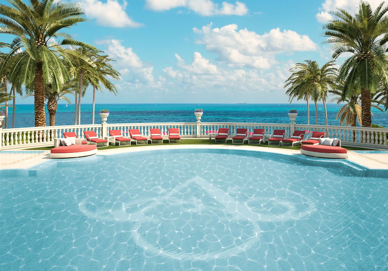 Palm-lined oceanfront pool terrace with loungers and direct water views at The Estates at Acqualina, Sunny Isles Beach, a community of luxury and ultra luxury condos.