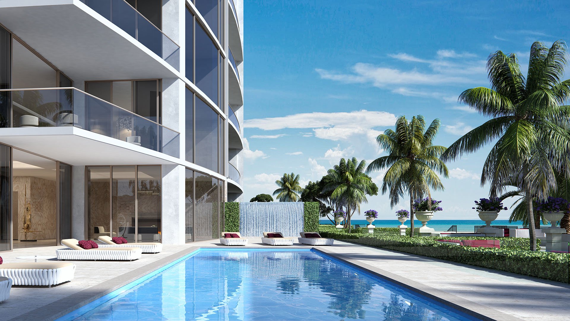 Private pool terrace beside a beachfront tower with palms and lawn at The Estates at Acqualina, Sunny Isles Beach, a community of luxury and ultra luxury condos.