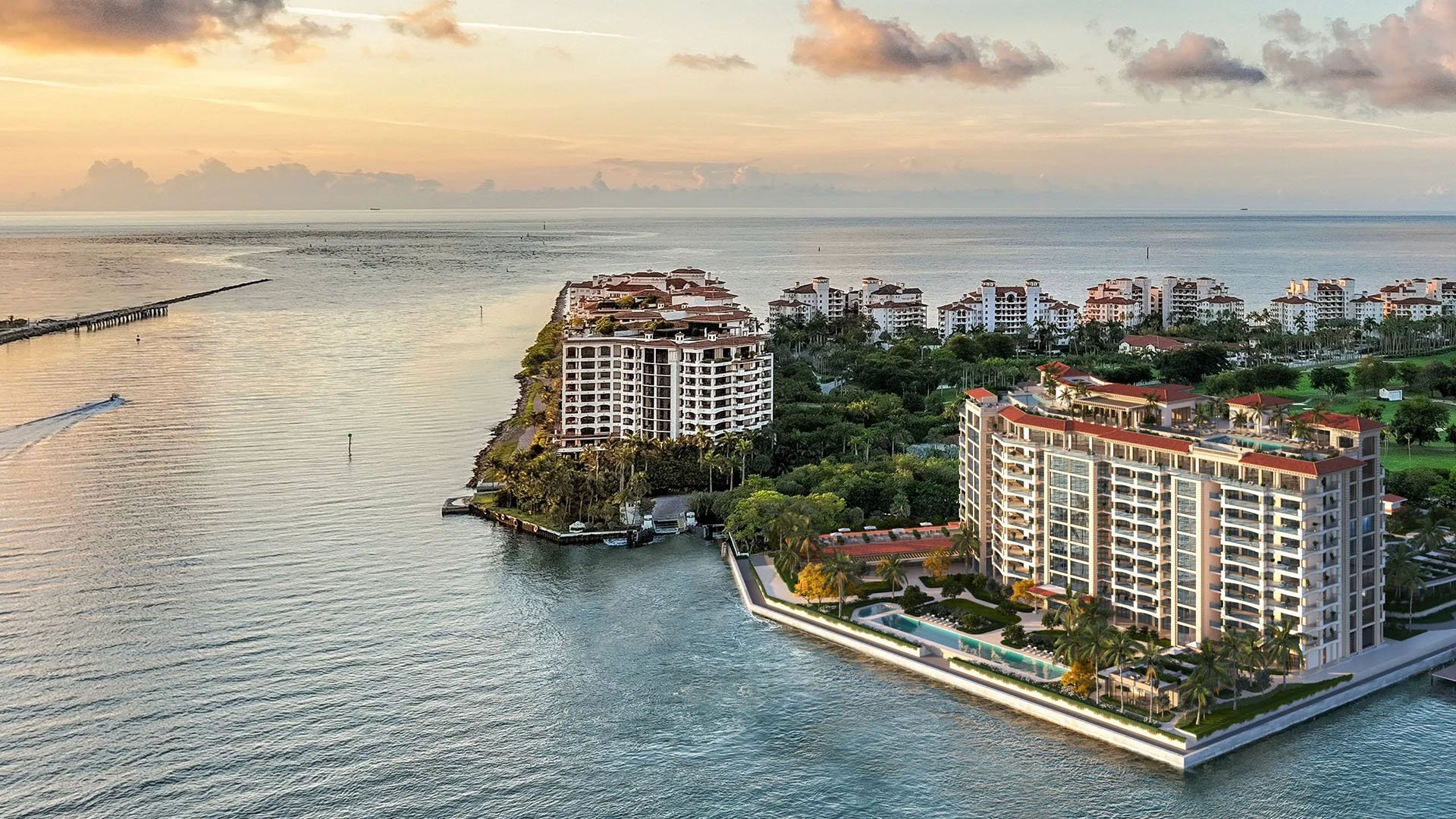 Sunset aerial of The Residences at Six Fisher Island, Fisher Island Miami Beach, Florida, waterfront tower and marina overlooking Biscayne Bay, highlighting luxury and ultra luxury preconstruction condos with resort amenities and bay views.