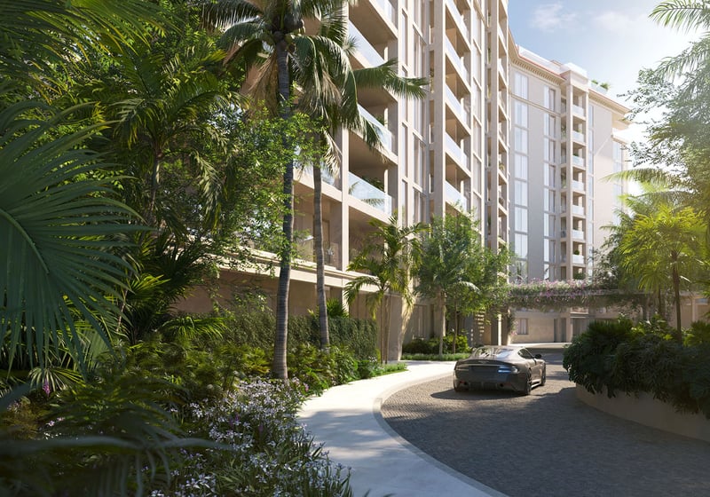 Tropical landscaped driveway approach to The Residences at Six Fisher Island on Fisher Island, Miami Beach, Florida, with palm-lined entry and modern facade, promoting luxury and ultra luxury preconstruction condos.