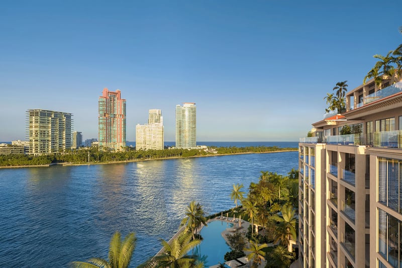 Hummingbird residence balcony view at The Residences at Six Fisher Island, Fisher Island Miami Beach Florida, overlooking Biscayne Bay and skyline; luxury and ultra luxury preconstruction condos with waterfront pool below.