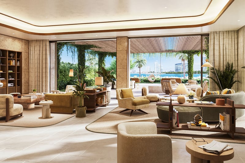 Waterfront living room at The Residences at Six Fisher Island, Fisher Island Miami Beach Florida, built-in bookcase and designer seating opening to terrace; luxury and ultra luxury preconstruction condos with Biscayne Bay views.