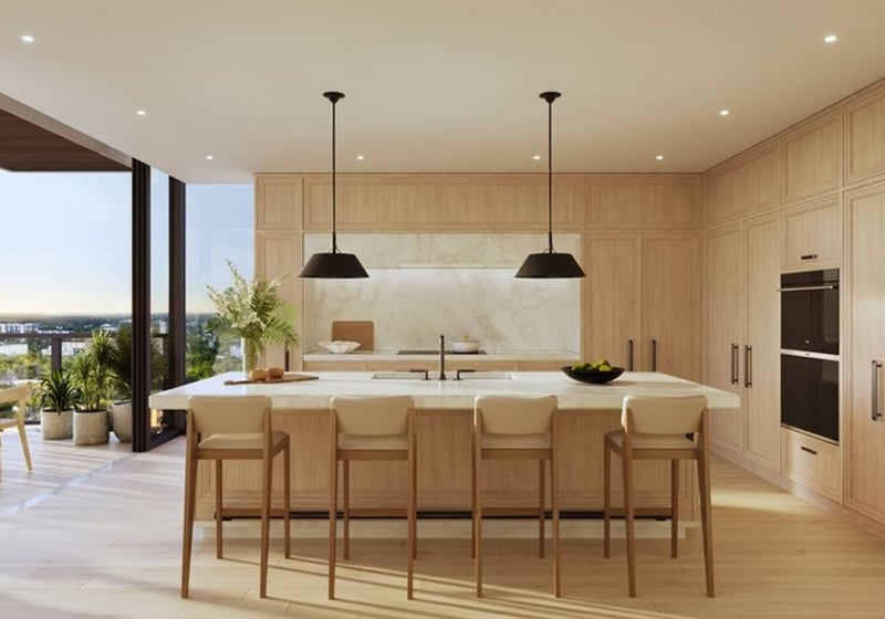 Chef kitchen at The Ritz-Carlton Residences, Fort Lauderdale, featuring an oversized island, custom wood cabinetry, and an open terrace with water views in one of the luxury and ultra luxury condos.