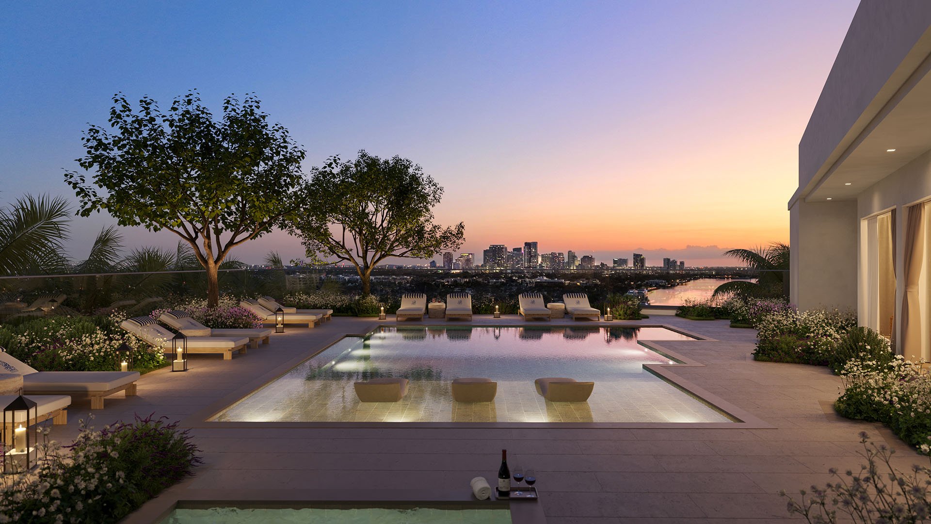 Rooftop pool terrace at The Ritz-Carlton Residences, Fort Lauderdale, featuring amenities for luxury and ultra luxury condos, with a wide waterway and skyline view, sun loungers, and a serene twilight setting.