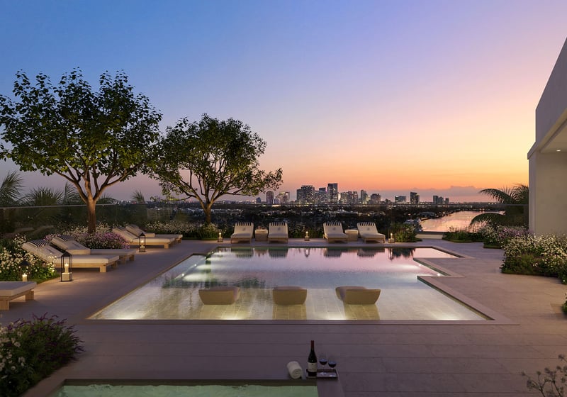 Rooftop pool terrace at The Ritz-Carlton Residences, Fort Lauderdale, featuring amenities for luxury and ultra luxury condos, with a wide waterway and skyline view, sun loungers, and a serene twilight setting.