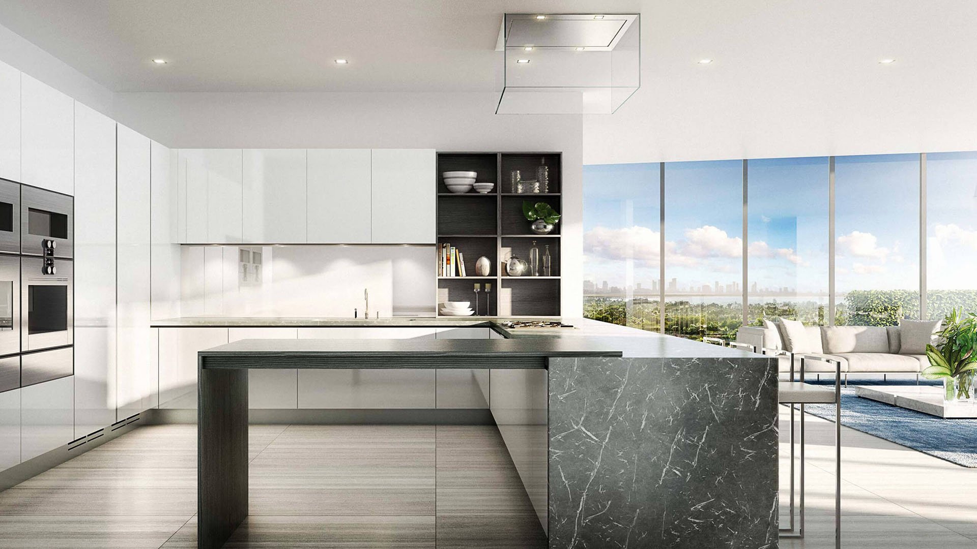 Chef kitchen with white cabinetry, a marble waterfall island and terrace views at The Ritz-Carlton Residences Miami Beach in Miami Beach, inside the luxury and ultra luxury condos.