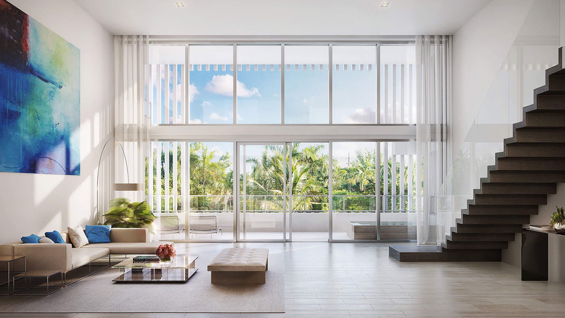 Double-height great room with an open staircase, a wall of glass and palm-filled terrace outlook at The Ritz-Carlton Residences Miami Beach in Miami Beach, inside the luxury and ultra luxury condos.