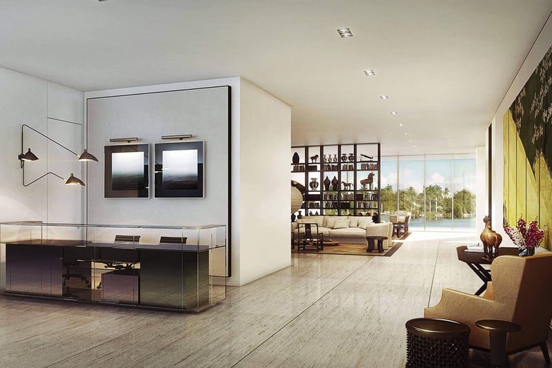Modern entry foyer with a glass console desk, framed artwork and an open view to the waterfront living area at The Ritz-Carlton Residences Miami Beach in Miami Beach, inside the luxury and ultra luxury condos.