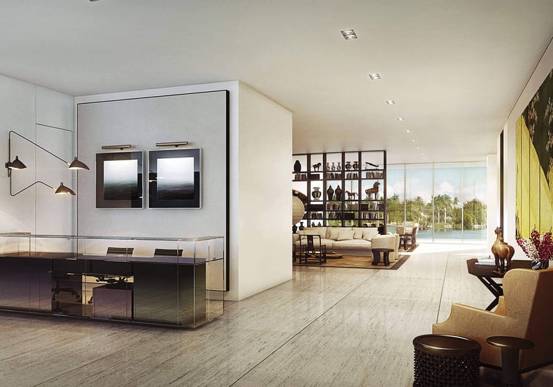 Modern entry foyer with a glass console desk, framed artwork and an open view to the waterfront living area at The Ritz-Carlton Residences Miami Beach in Miami Beach, inside the luxury and ultra luxury condos.