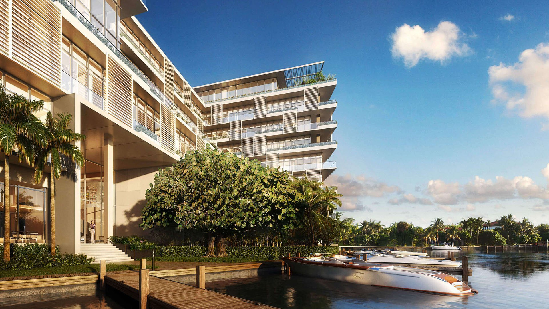 Waterfront exterior with a private dock and speedboat at The Ritz-Carlton Residences Miami Beach in Miami Beach, showing luxury and ultra luxury condos along the water.