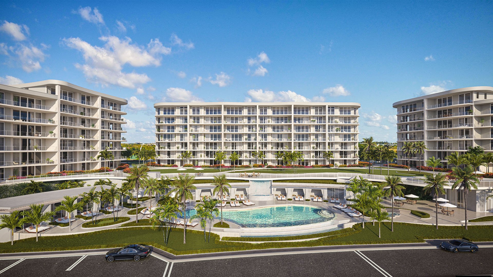 Courtyard resort pool and waterfall amenity deck at The Ritz-Carlton Residences Palm Beach Gardens in Palm Beach Gardens, Florida, showcasing luxury and ultra luxury preconstruction condos with landscaped cabanas and central building views.