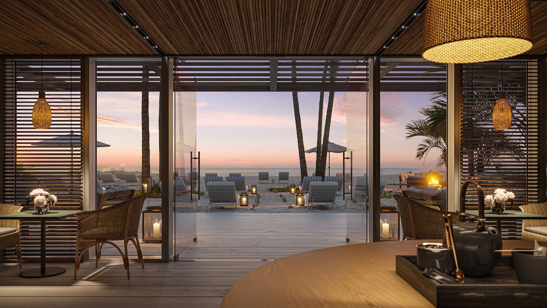 The Ritz-Carlton Residences Pompano Beach, Florida beach club at sunset with oceanfront lounge, lantern-lit walkway and firepit, showcasing luxury and ultra luxury preconstruction condos with private beach access.