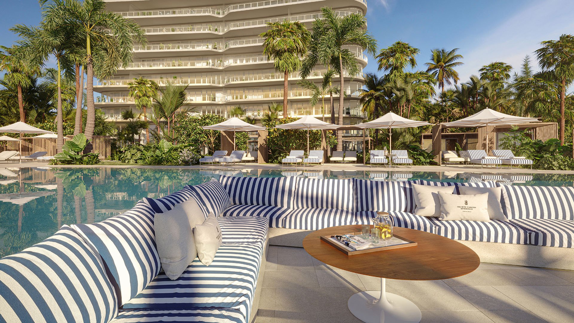 Poolside sunken lounge with striped sectional seating and cabanas at The Ritz-Carlton Residences Pompano Beach, Florida Beach Tower, emphasizing luxury and ultra luxury preconstruction condos with elevated pool amenities.