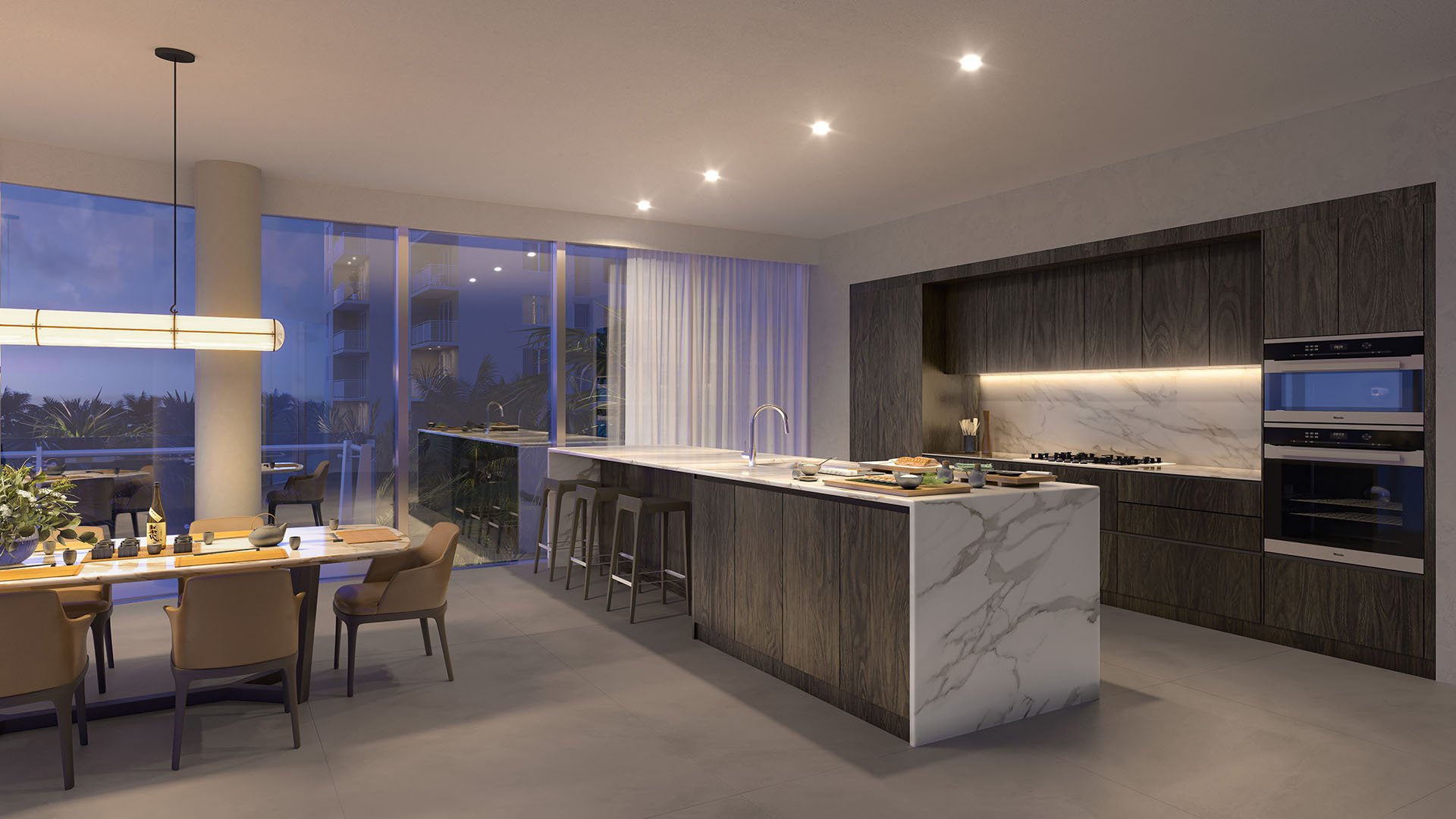 Evening view of Marina Tower Residence 01 kitchen and dining at The Ritz-Carlton Residences Pompano Beach, Florida, featuring marble waterfall island and designer lighting, showcasing luxury and ultra luxury preconstruction condos interiors.