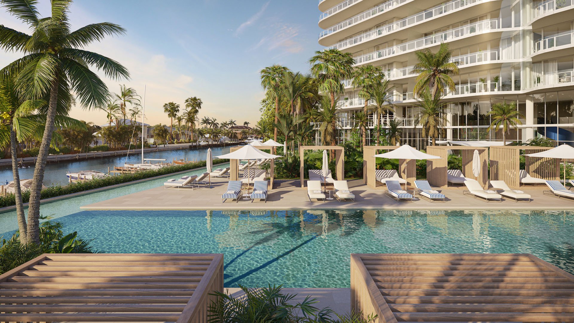 The Ritz-Carlton Residences Pompano Beach Marina Tower waterfront pool deck with cabanas and sun loungers overlooking the marina canal, highlighting luxury and ultra luxury preconstruction condos amenities in Pompano Beach, Florida.