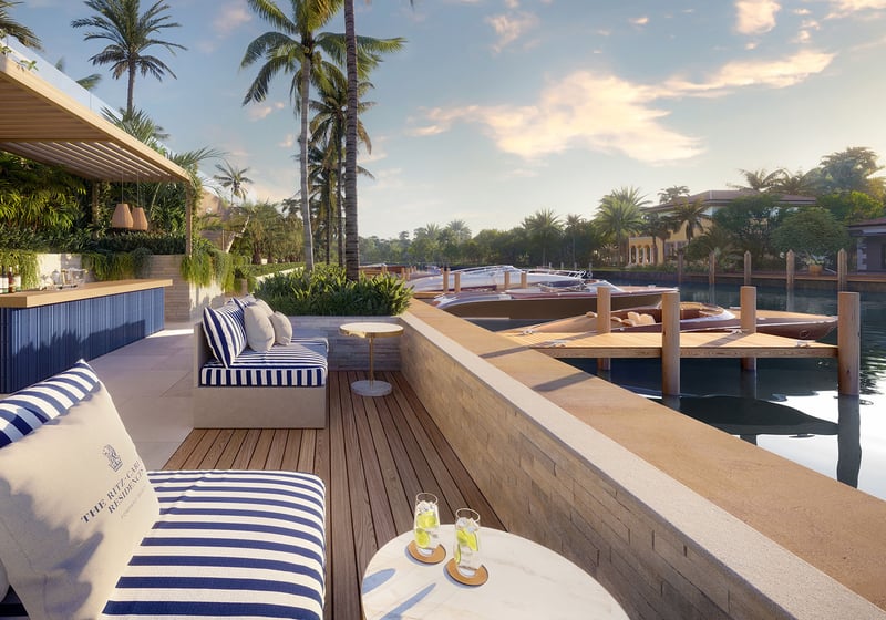 Sundowners outdoor bar lounge at The Ritz-Carlton Residences Pompano Beach Marina Tower with striped seating, sunset cocktails, private dock and yachts on the marina canal, showcasing luxury and ultra luxury preconstruction waterfront condos in Pompano Beach, Florida.