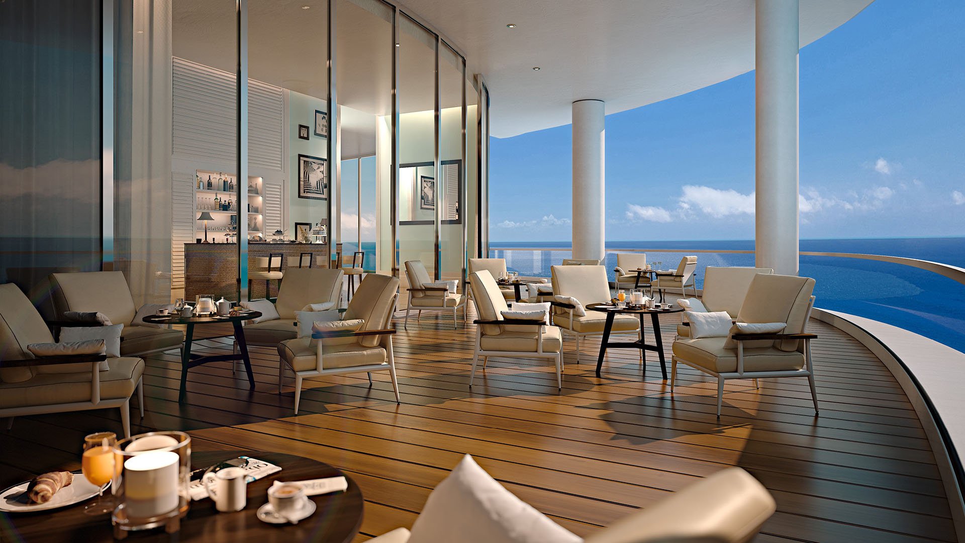 Oceanfront club terrace with lounge seating and a bar opening to the sea at The Ritz-Carlton Residences, Sunny Isles Beach, luxury and ultra luxury condos in Sunny Isles Beach.