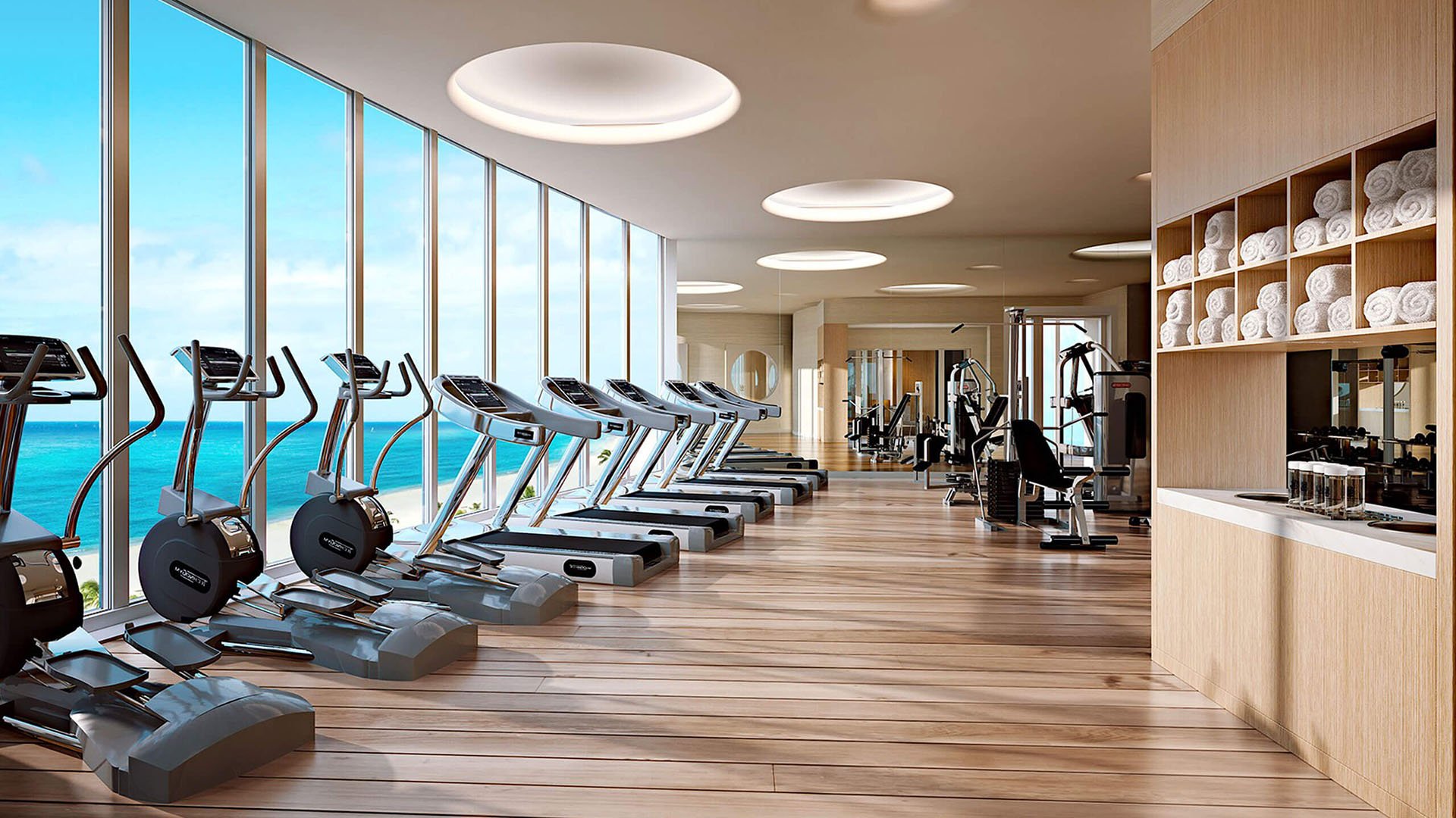 Oceanfront fitness center with cardio machines and floor-to-ceiling windows at The Ritz-Carlton Residences, Sunny Isles Beach, luxury and ultra luxury condos in Sunny Isles Beach.