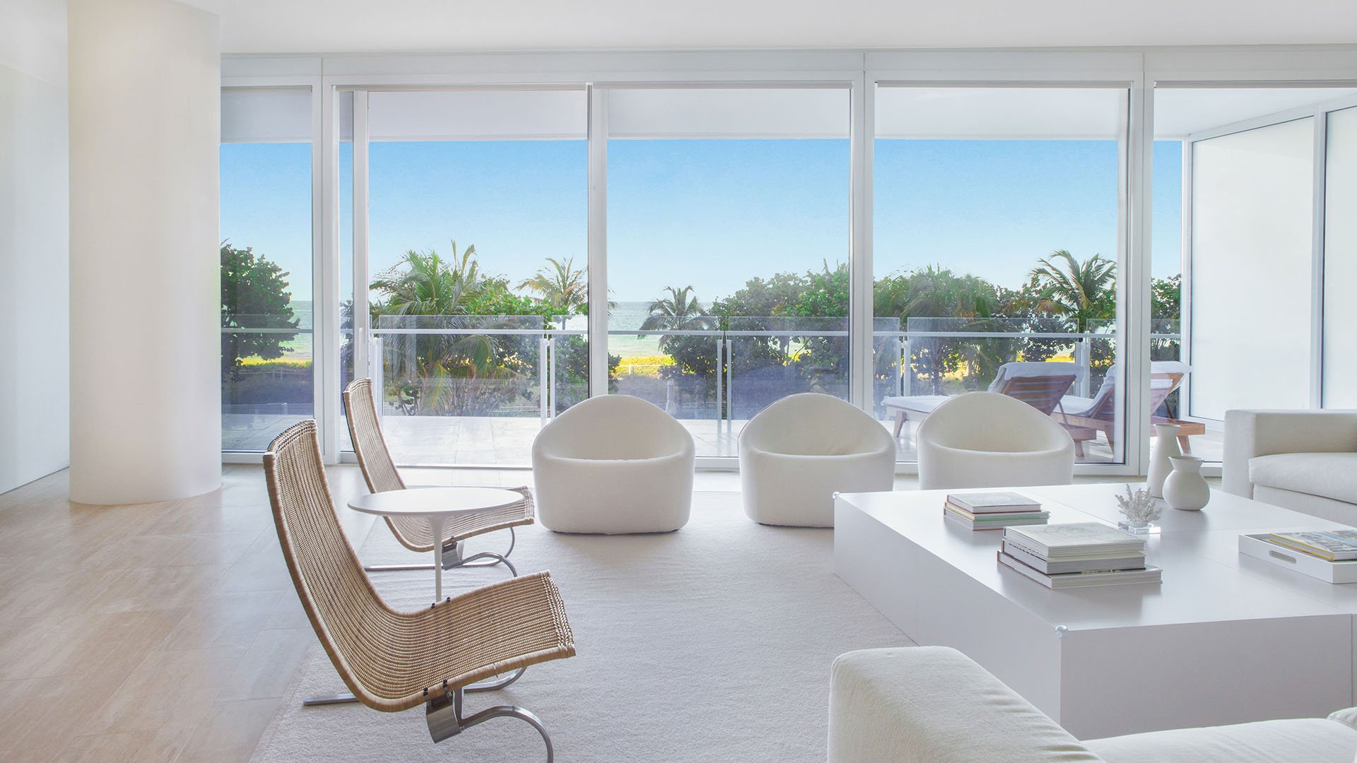 Living room with a wall of glass, sculptural chairs, and tranquil garden views at The Surf Club Four Seasons, Fort Lauderdale luxury and ultra luxury condos.