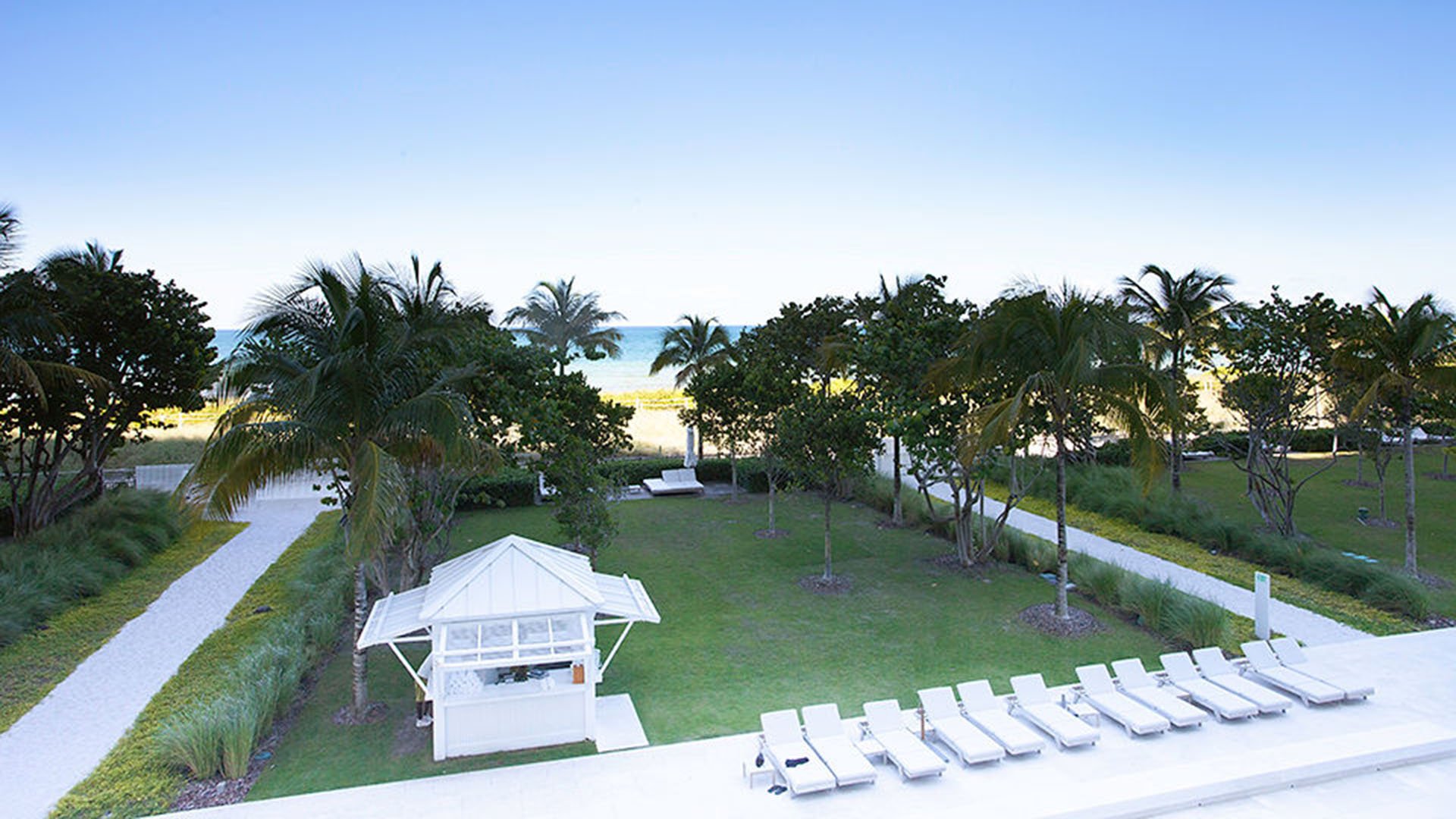 Elevated view of the oceanfront lawn, cabana, and rows of sun loungers at The Surf Club Four Seasons, Fort Lauderdale luxury and ultra luxury condos.