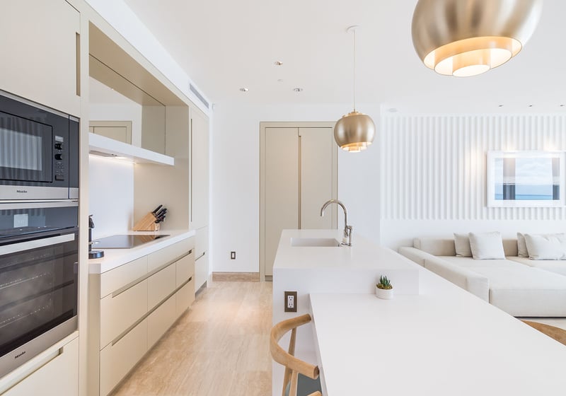Open-concept white chef kitchen with a long island, built-in ovens, and lounge seating at The Surf Club Four Seasons, Fort Lauderdale luxury and ultra luxury condos.