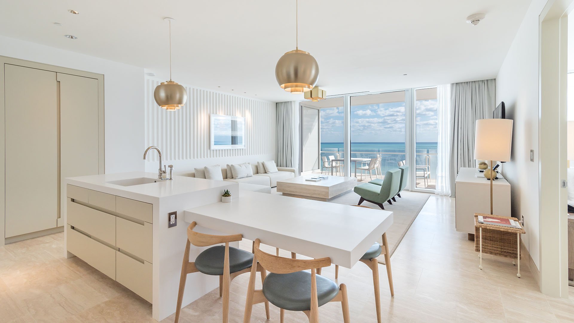 Bright open-plan kitchen and living area with island seating and ocean-facing glass doors at The Surf Club Four Seasons, Fort Lauderdale luxury and ultra luxury condos.