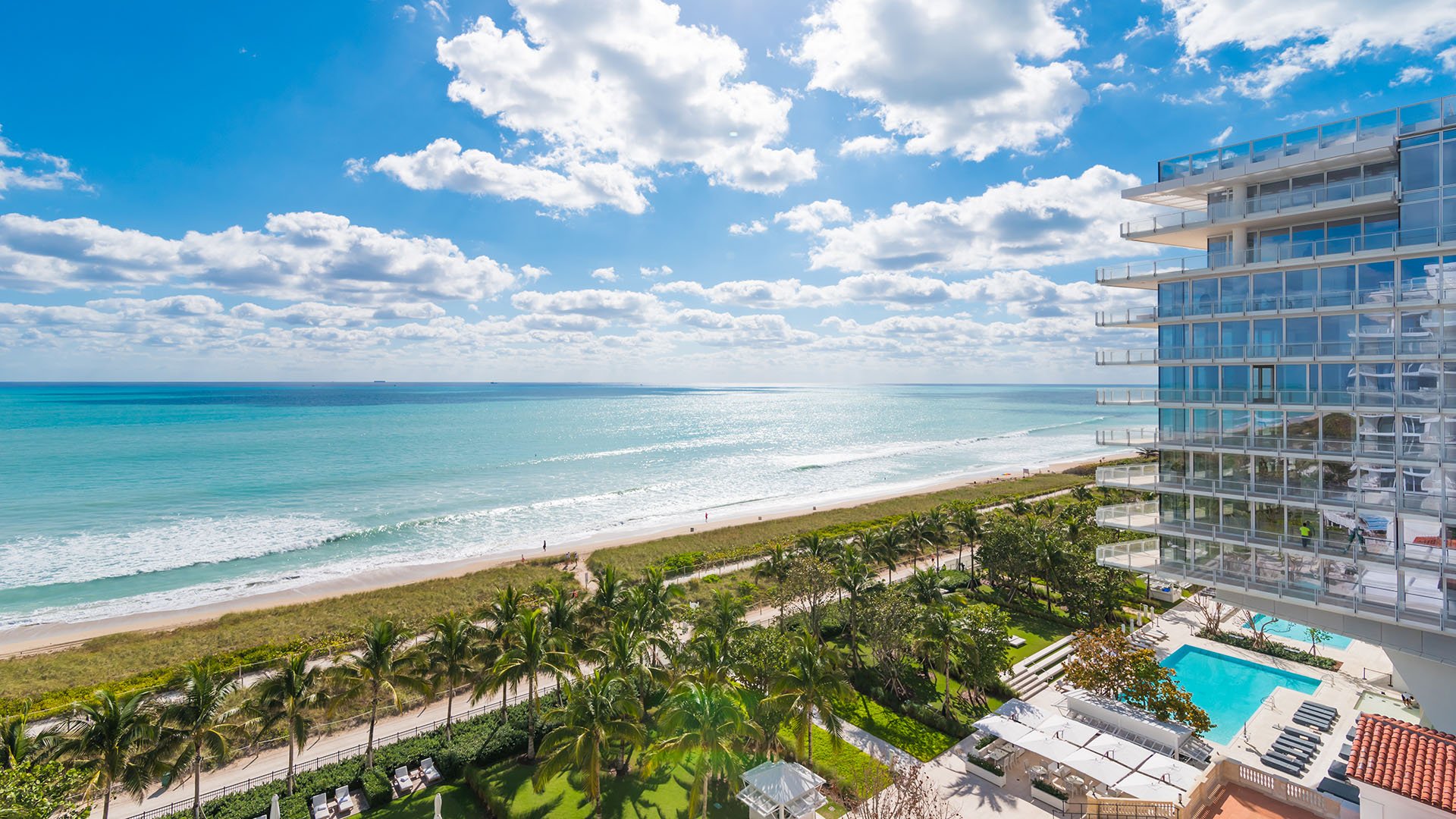 Tower-edge ocean view over the resort pool, palms, and beachfront lawn at The Surf Club Four Seasons, Fort Lauderdale luxury and ultra luxury condos.