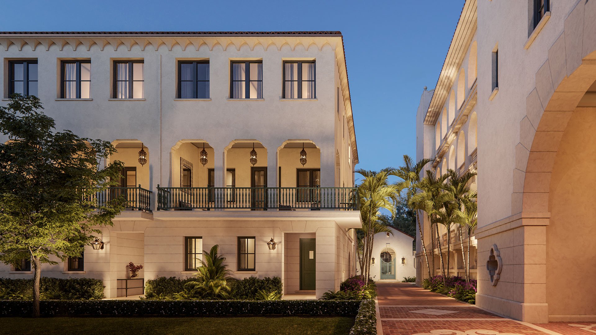 The Village at Coral Gables promenade in Coral Gables, Miami evening walkway between Spanish Mediterranean buildings with arches, palm trees and lantern lighting; luxury and ultra luxury preconstruction condos.