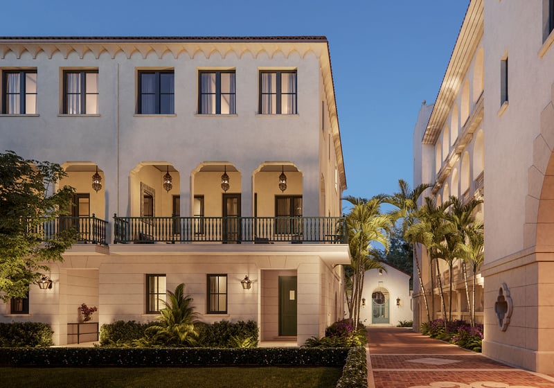 The Village at Coral Gables promenade in Coral Gables, Miami evening walkway between Spanish Mediterranean buildings with arches, palm trees and lantern lighting; luxury and ultra luxury preconstruction condos.