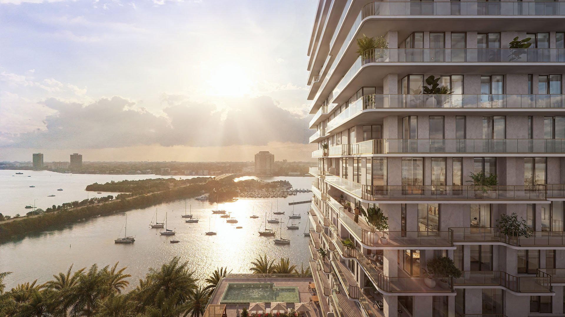 Aerial bayfront view of the tower and surrounding shoreline at Tula Residences in North Bay Village, showcasing luxury and ultra luxury condos with curved terraces, waterfront positioning, and a prominent coastal skyline presence.