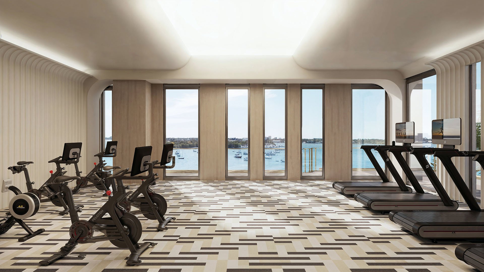 Bayfront fitness center with treadmills, spin bikes, and water views at Tula Residences in North Bay Village, reinforcing luxury and ultra luxury condos with wellness amenities and a bright modern exercise space.