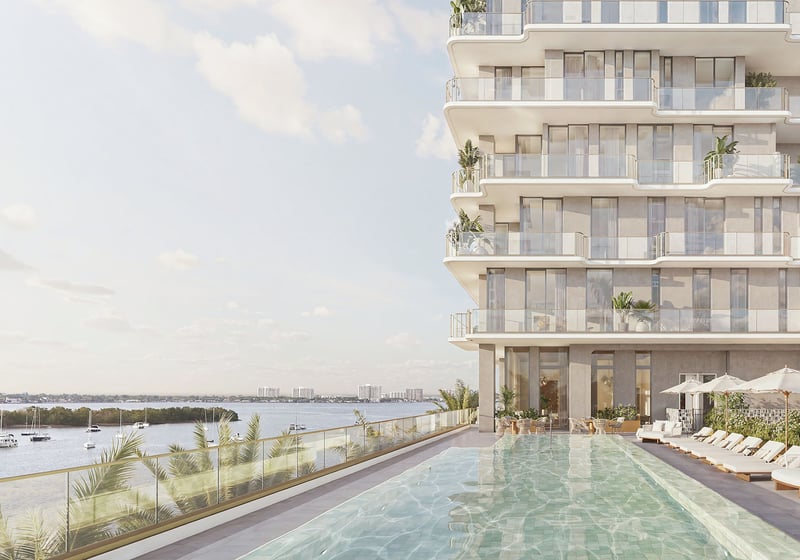 Bayfront pool deck lined with loungers beside the tower facade at Tula Residences in North Bay Village, presenting luxury and ultra luxury condos with resort-style waterfront amenities and contemporary architectural lines.