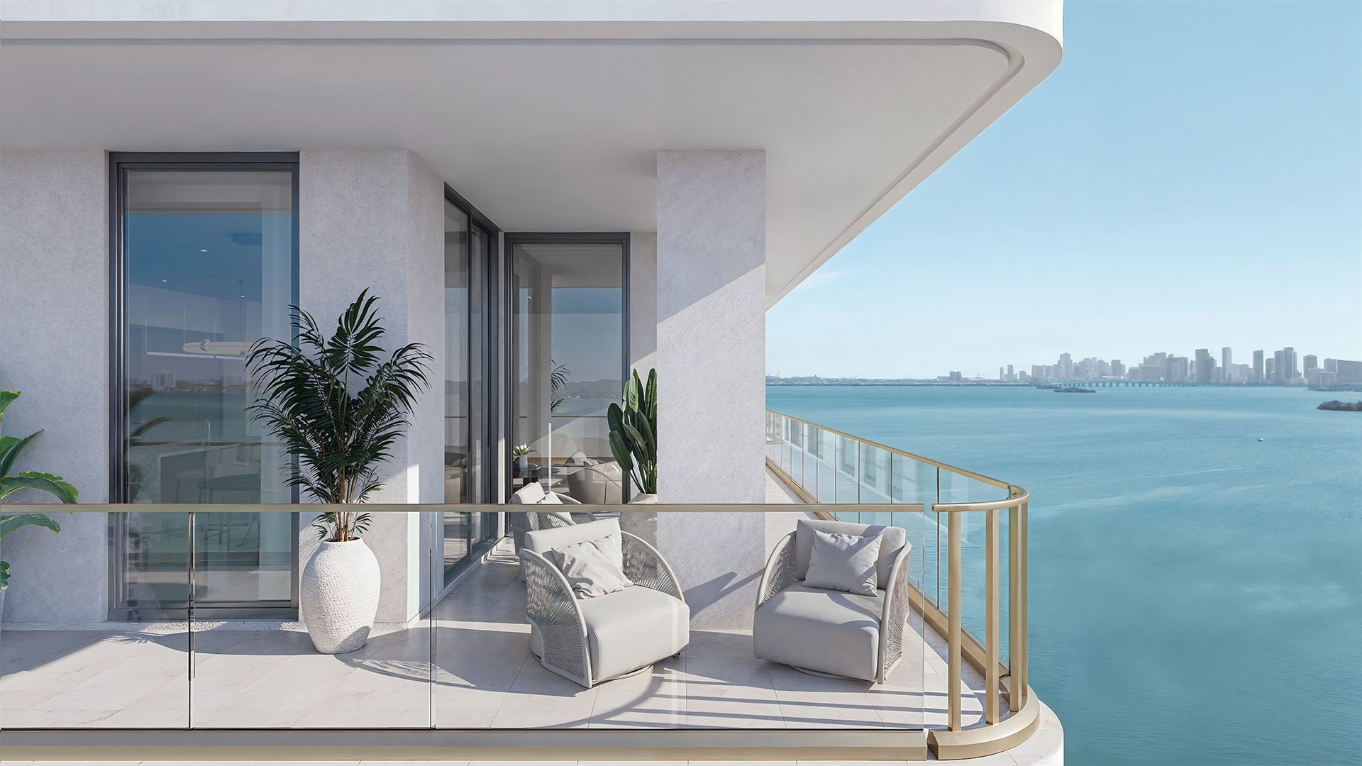 Corner terrace with lounge chairs and a glass railing overlooking the bay at Tula Residences in North Bay Village, highlighting luxury and ultra luxury condos with intimate outdoor seating and open water views.