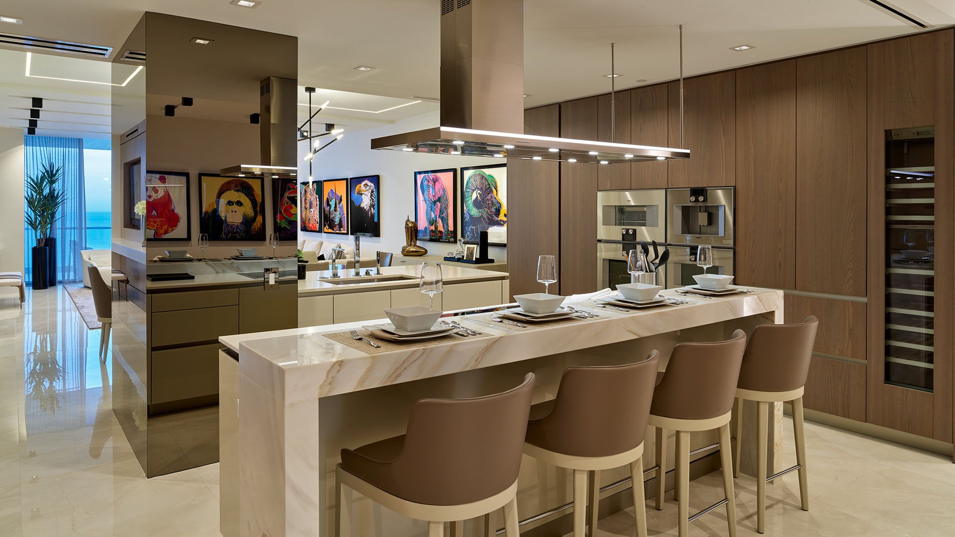 Turnberry Ocean Club in Sunny Isles Beach luxury and ultra luxury condos showcase a chef kitchen with a marble breakfast bar, wood cabinetry, and polished stone floors.